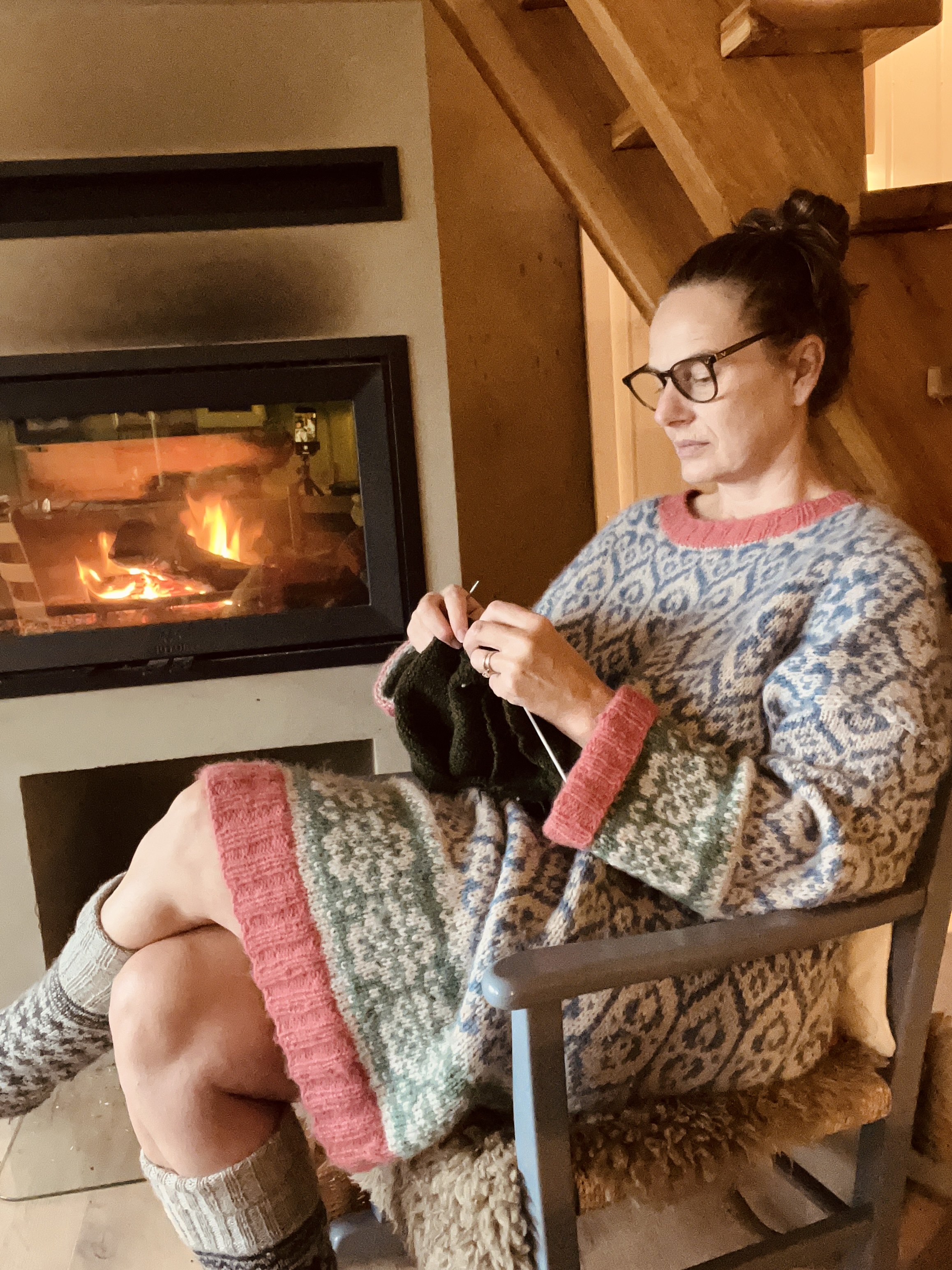 Kvinde strikker ved peisen